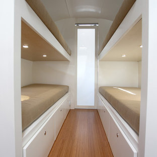 Modelo de dormitorio contemporáneo, pequeño, con paredes blancas y suelo de bambú