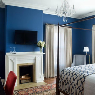 Diseño de habitación de invitados tradicional, grande, con paredes azules, chimenea tradicional, marco de chimenea de baldosas y/o azulejos, suelo de madera en tonos medios y suelo marrón