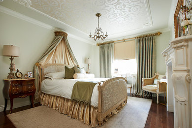 Пример оригинального дизайна: хозяйская спальня в классическом стиле с зелеными стенами, темным паркетным полом и стандартным камином