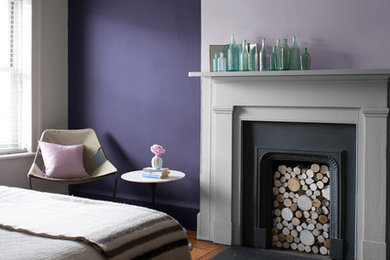 Bedroom - medium tone wood floor bedroom idea in Vancouver with purple walls, a standard fireplace and a plaster fireplace
