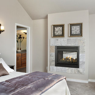 Imagen de dormitorio principal, clásico, de tamaño medio, con paredes beige, moqueta, chimeneas suspendidas, marco de chimenea de baldosas y/o azulejos y suelo gris