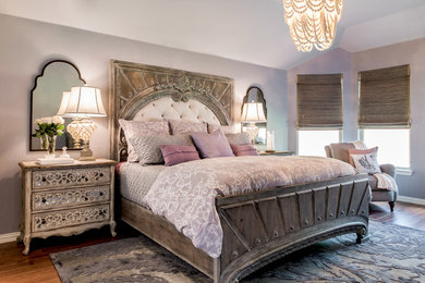 Modelo de dormitorio principal tradicional de tamaño medio sin chimenea con paredes púrpuras y suelo de madera en tonos medios