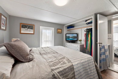 ニューヨークにある中くらいなビーチスタイルのおしゃれな客用寝室 (グレーの壁、ラミネートの床、暖炉なし、マルチカラーの床) のレイアウト