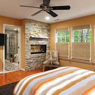 Mittelgroßes Klassisches Hauptschlafzimmer mit oranger Wandfarbe, braunem Holzboden, Kaminumrandung aus Stein, Tunnelkamin und orangem Boden in Washington, D.C.
