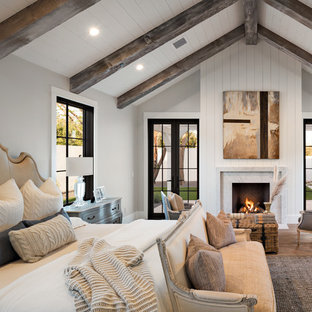 Country Schlafzimmer mit grauer Wandfarbe, braunem Holzboden, Kamin, Kaminumrandung aus Stein und braunem Boden in Phoenix