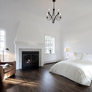 Ejemplo de dormitorio principal, clásico renovado, grande, con paredes blancas, suelo de madera oscura, chimenea tradicional y marco de chimenea de metal