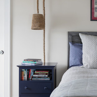 Imagen de habitación de invitados costera, de tamaño medio, sin chimenea, con paredes beige, suelo de madera clara y suelo azul
