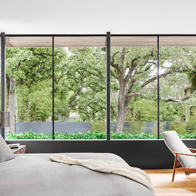 Example of a trendy medium tone wood floor and brown floor bedroom design in Austin with white walls