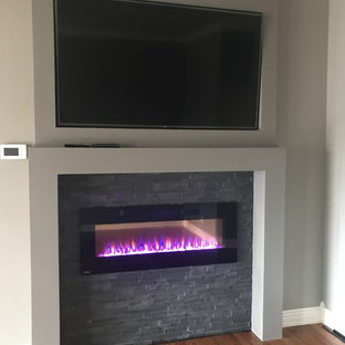 Modelo de dormitorio principal, clásico renovado, con paredes grises, suelo de madera clara, chimeneas suspendidas y marco de chimenea de baldosas y/o azulejos