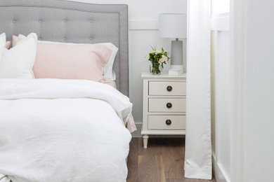 バンクーバーにある中くらいなコンテンポラリースタイルのおしゃれな客用寝室 (白い壁、無垢フローリング、暖炉なし、茶色い床) のインテリア