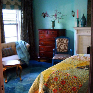 Modelo de dormitorio principal, bohemio, de tamaño medio, con paredes verdes, suelo de madera clara, chimenea tradicional y marco de chimenea de ladrillo