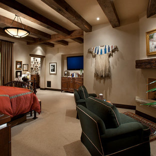 Foto de dormitorio principal, rural, grande, con paredes beige, moqueta, chimenea de esquina y marco de chimenea de yeso