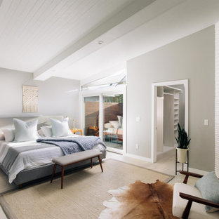 Foto di una camera da letto minimalista con pareti grigie, parquet chiaro, camino ad angolo, cornice del camino piastrellata, pavimento beige e soffitto a volta