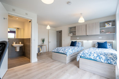Ejemplo de habitación de invitados minimalista pequeña con paredes blancas, suelo de madera clara y suelo marrón