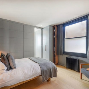 Design ideas for a small eclectic guest bedroom in London with grey walls, light hardwood flooring and brown floors.
