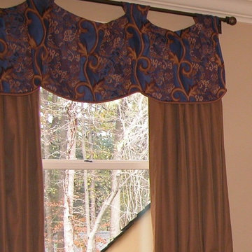Unique valance hung above window. Drapes for privacy.