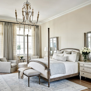 This is an example of a large mediterranean master bedroom in Phoenix with beige walls, medium hardwood floors and brown floor.