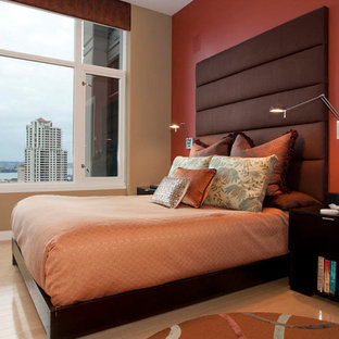 Modelo de dormitorio principal, contemporáneo, grande, sin chimenea, con paredes rojas y suelo de madera clara