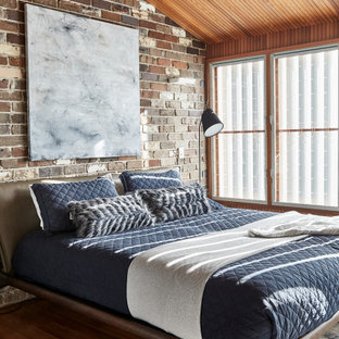 Industrial master bedroom in Sydney with dark hardwood floors and brown floor.
