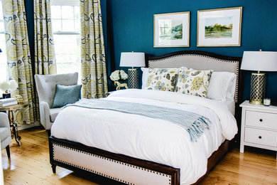 Diseño de dormitorio principal tradicional renovado sin chimenea con paredes azules y suelo de madera clara