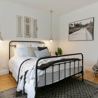 Design ideas for a beach style guest bedroom in Adelaide with white walls, medium hardwood floors and beige floor.