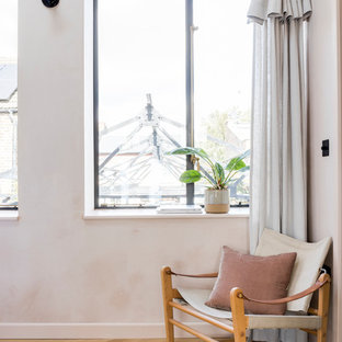 Exemple d'une chambre parentale industrielle avec un mur rose et un sol en bois clair.