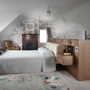 Modelo de dormitorio principal, bohemio, de tamaño medio, con paredes blancas, suelo de madera pintada, chimenea tradicional y marco de chimenea de madera