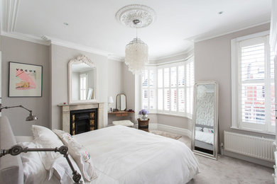 ロンドンにある広いトランジショナルスタイルのおしゃれな主寝室 (グレーの壁、カーペット敷き、標準型暖炉、石材の暖炉まわり、照明) のインテリア