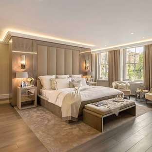 Modelo de dormitorio principal, tradicional renovado, extra grande, con paredes beige, suelo de madera en tonos medios y suelo marrón