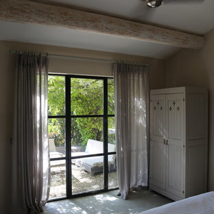 Imagen de habitación de invitados rural, de tamaño medio, con paredes beige y suelo de cemento