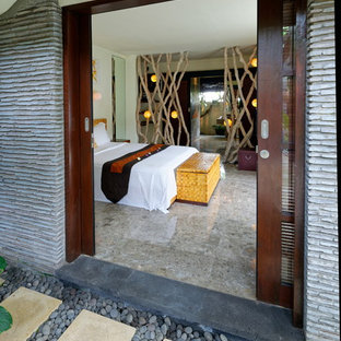Imagen de dormitorio principal, tropical, grande, con paredes blancas, suelo de piedra caliza y suelo gris