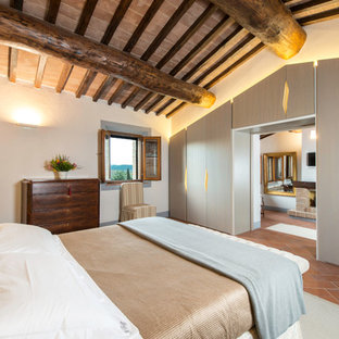 Diseño de dormitorio principal, actual, grande, con paredes blancas, suelo de ladrillo, chimenea tradicional y marco de chimenea de piedra