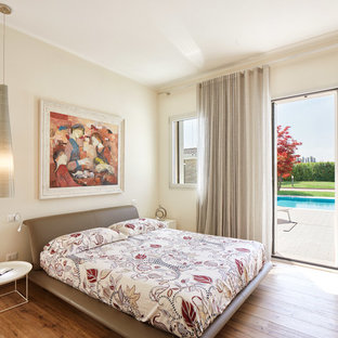 Immagine di una camera matrimoniale design con pareti beige, pavimento in legno massello medio e pavimento marrone