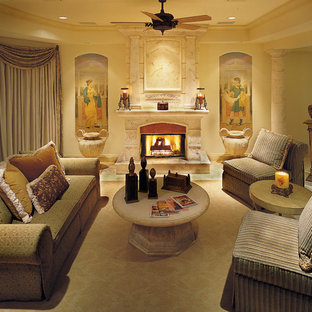 Modelo de dormitorio principal, mediterráneo, grande, con paredes beige, suelo de travertino, chimenea tradicional y marco de chimenea de piedra