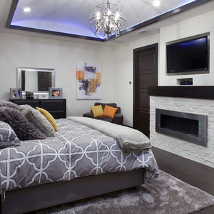 Imagen de dormitorio principal, contemporáneo, de tamaño medio, con paredes blancas, suelo de madera oscura, marco de chimenea de ladrillo y chimenea lineal