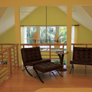 Diseño de dormitorio tipo loft, exótico, de tamaño medio, con paredes amarillas y suelo de bambú