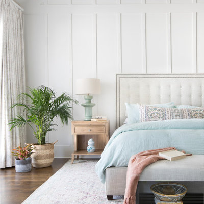 Example of a large beach style master medium tone wood floor, brown floor and wainscoting bedroom design in Charleston with white walls
