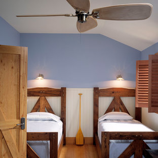 Ejemplo de habitación de invitados rural, de tamaño medio, sin chimenea, con paredes azules, suelo de madera clara y suelo marrón