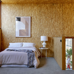 Design ideas for an industrial loft-style bedroom in Newcastle - Maitland with brown walls, carpet, grey floor, wood and wood walls.