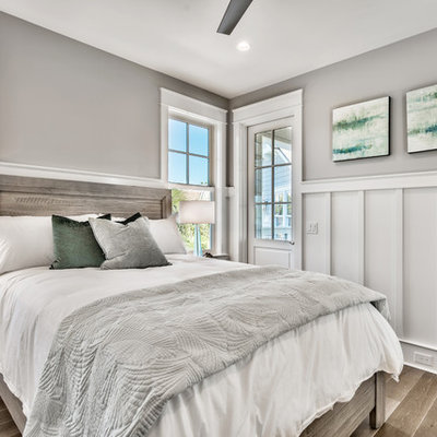 Example of a mid-sized beach style guest dark wood floor and brown floor bedroom design in Miami with gray walls and no fireplace