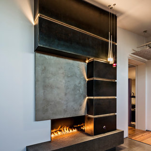 Modelo de dormitorio principal, contemporáneo, grande, con paredes blancas, chimenea tradicional, marco de chimenea de metal, suelo gris y suelo de cemento