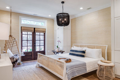 Example of a beach style medium tone wood floor and brown floor bedroom design in Houston with beige walls