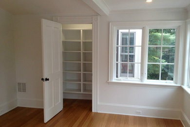 Mid-sized elegant guest medium tone wood floor bedroom photo in Boston with white walls