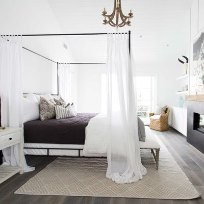 Example of a large beach style master dark wood floor bedroom design in Orange County with white walls and a ribbon fireplace