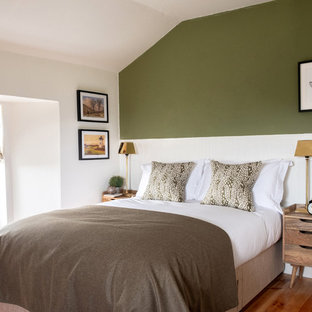 This is an example of a large rural guest bedroom in Edinburgh with medium hardwood flooring, white walls and brown floors.