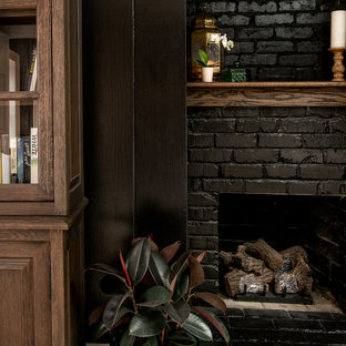 Ejemplo de dormitorio principal, clásico renovado, grande, con paredes negras, suelo de madera oscura, chimenea tradicional, marco de chimenea de ladrillo y suelo marrón