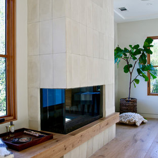 Foto de dormitorio principal, contemporáneo, de tamaño medio, con paredes blancas, suelo de piedra caliza, chimenea de doble cara y marco de chimenea de baldosas y/o azulejos