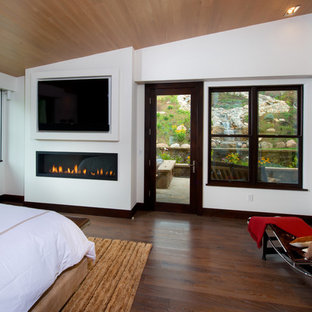 Foto de dormitorio principal, actual, de tamaño medio, con paredes blancas, suelo de madera oscura, chimenea lineal y marco de chimenea de metal