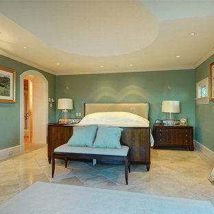 Modelo de dormitorio mediterráneo con paredes beige, suelo de piedra caliza, chimenea tradicional y marco de chimenea de piedra