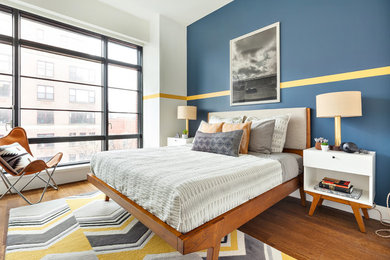 Example of a mid-sized trendy guest medium tone wood floor bedroom design in New York with multicolored walls and no fireplace